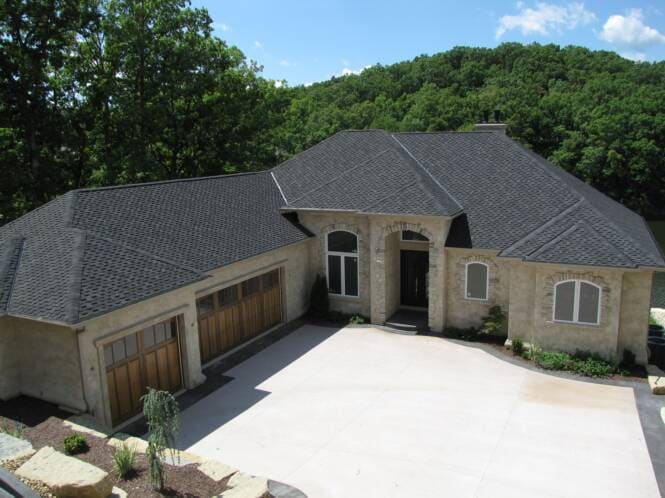 Single-story lake home in stone and stucco with a three-car garage