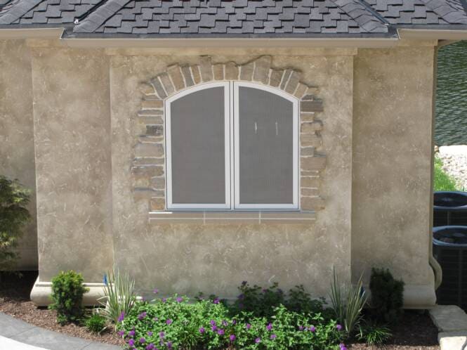 Arched window with a cut-stone surround set into a stucco wall