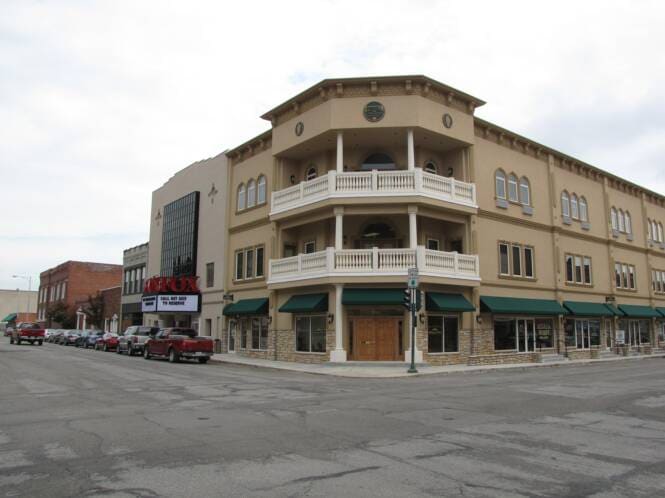 Three-story mixed-use building on a downtown corner, stucco above storefronts