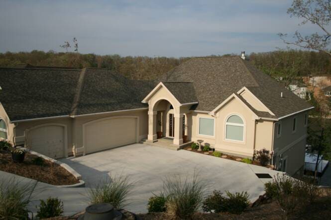 Hillside home in tan stucco with an arched entry and tall windows