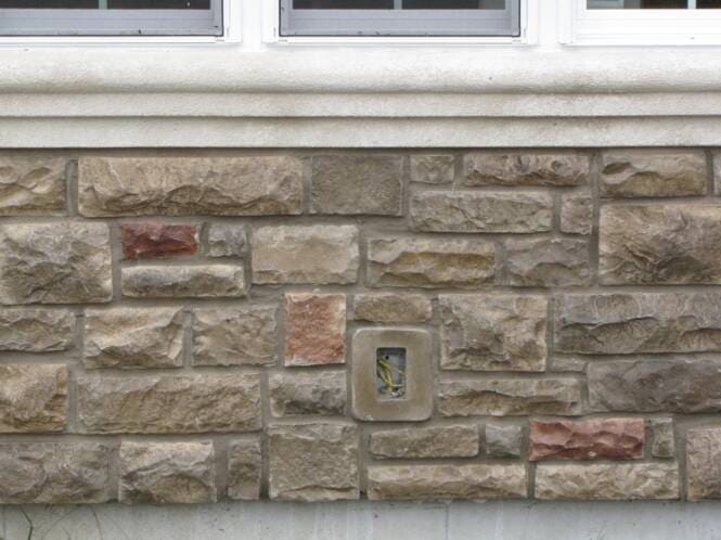 Close-up of synthetic stone veneer coursing around a wall outlet