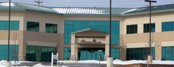 Two-story office building in snow, EIFS facade with teal glazing