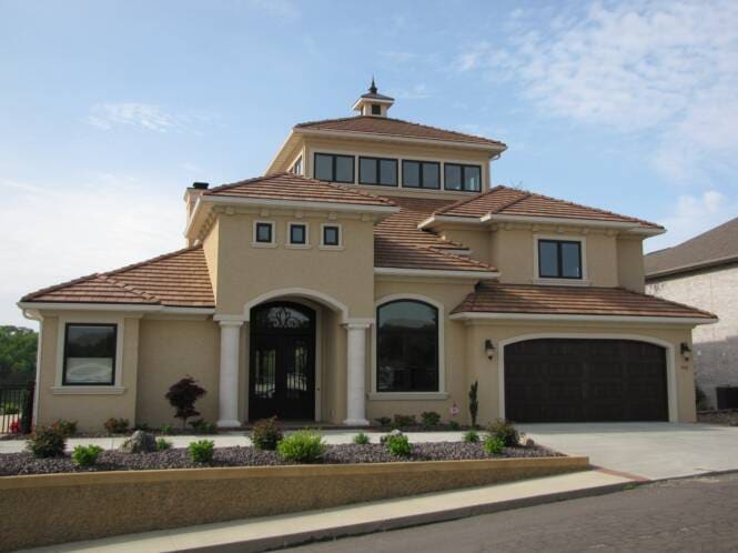 Two-story stucco home with a cupola and arched window heads
