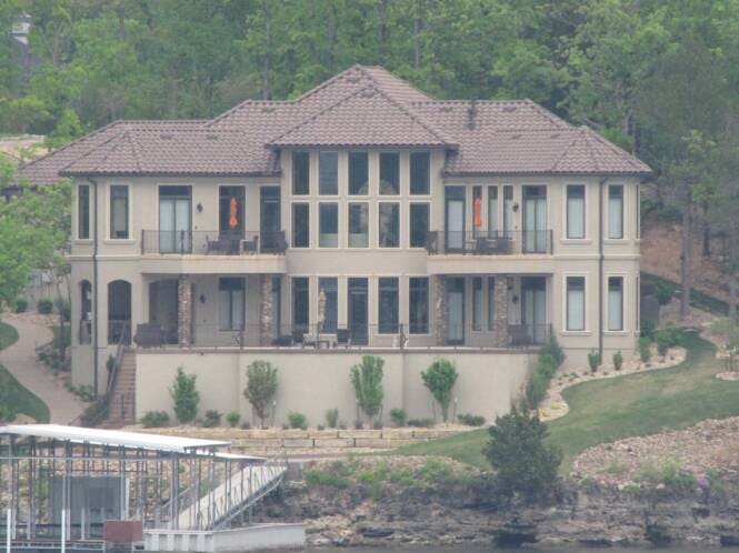 Multi-story lake home with a tile roof and columned balconies