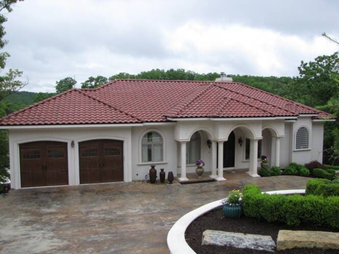 Home with a tile roof, stucco columns and an arched entry porch